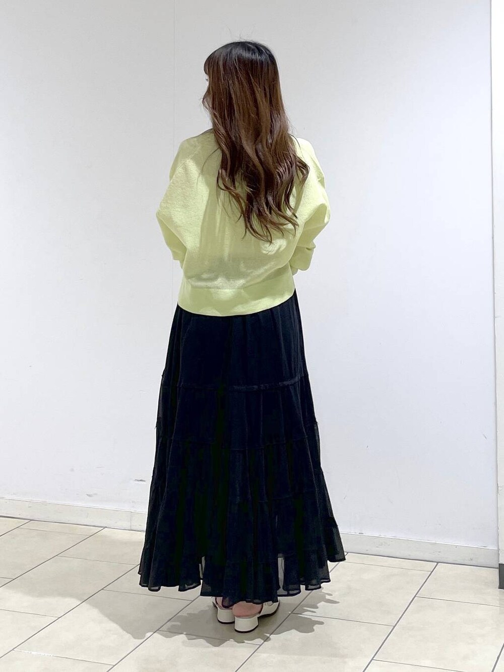 ブラック系のショルダーバッグ、ホワイト系のパンプス、グリーン系のカーディガン/ボレロを着用したレディースの春コーディネートの4枚目の写真