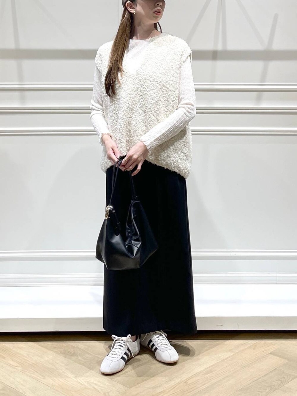 ブラック系のショルダーバッグ、ホワイト系のスニーカー、ホワイト系のTシャツ/カットソーを着用したレディースの冬コーディネートの2枚目の写真