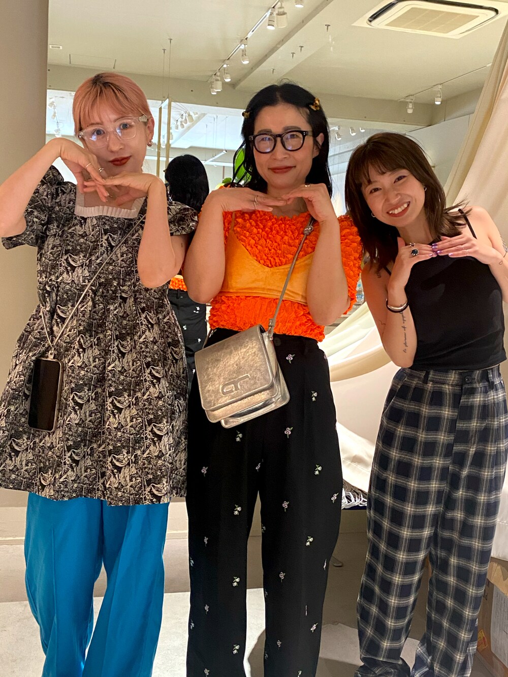 オレンジ系のTシャツ/カットソー、オレンジ系のその他トップス、ブラック系のスラックスを着用したレディースの夏コーディネートの2枚目の写真