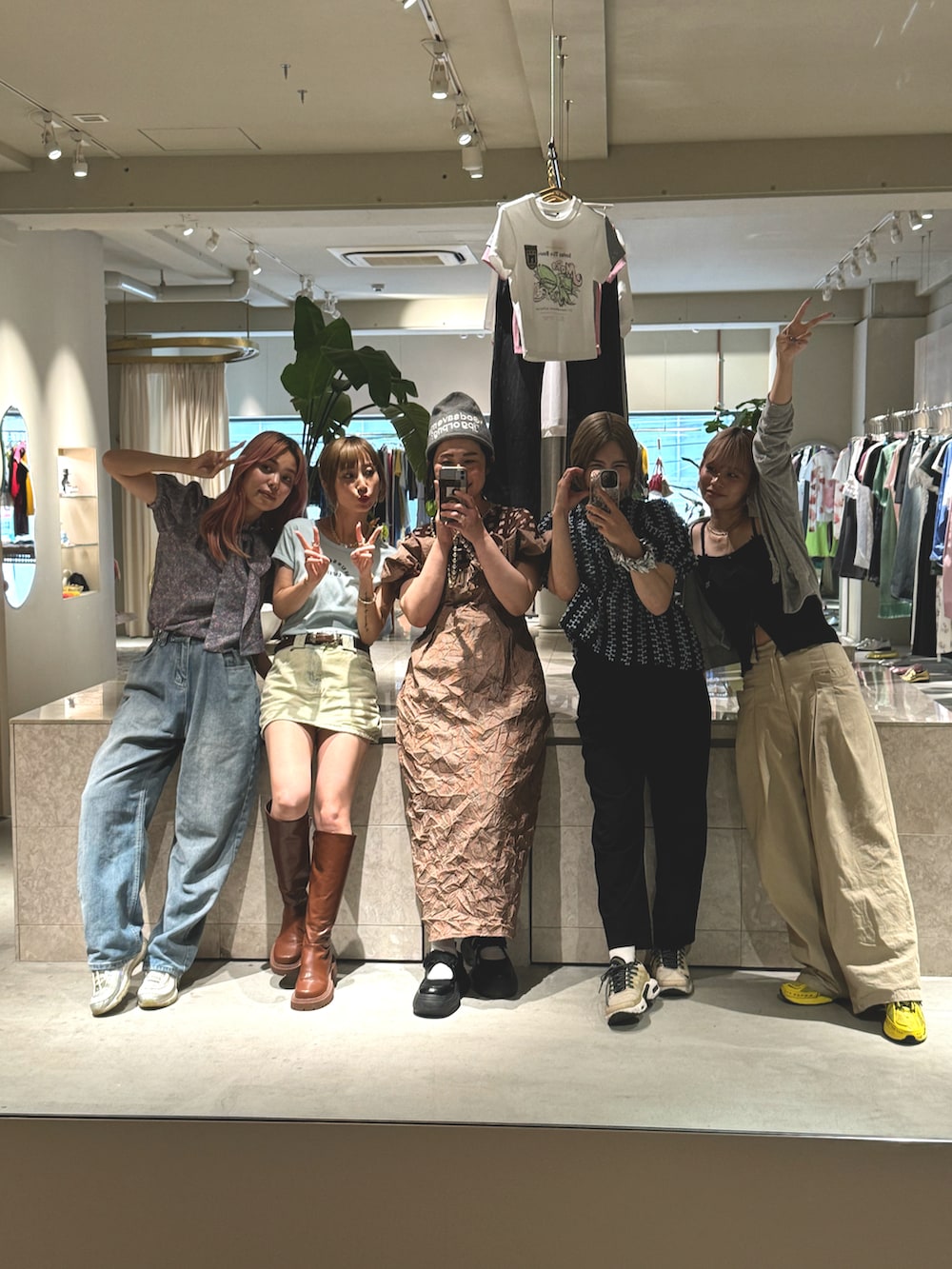 ブラウン系のワンピース、ブラウン系のTシャツ/カットソー、ブラック系のスニーカーを着用したレディースの夏コーディネートの2枚目の写真