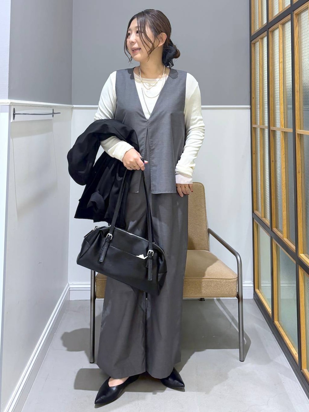 ブラック系のボストンバッグ、ホワイト系のTシャツ/カットソー、ブラック系のパンプスを着用したレディースの冬コーディネートの2枚目の写真