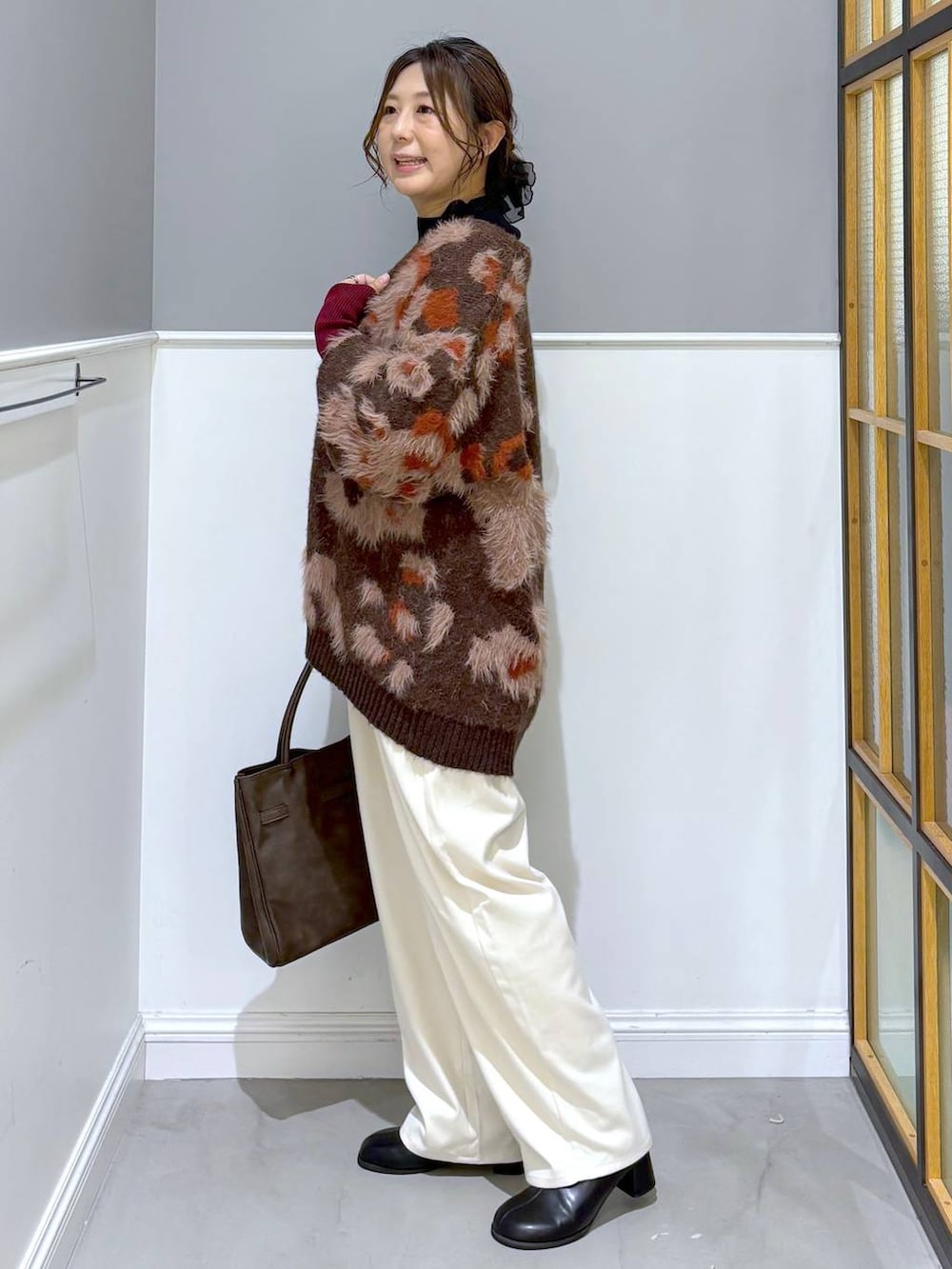 ブラック系のニット/セーター、ホワイト系のその他パンツ、ブラウン系のトートバッグを着用したレディースの秋コーディネートの3枚目の写真