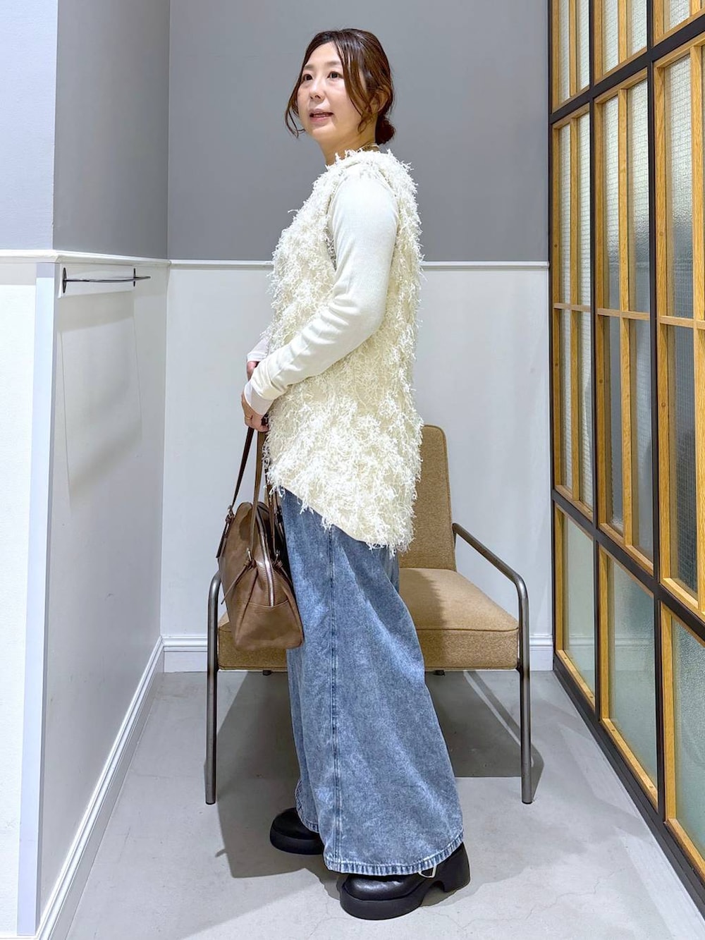 ブラック系のサンダル、ブラウン系のボストンバッグ、ホワイト系のTシャツ/カットソーを着用したレディースの冬コーディネートの2枚目の写真