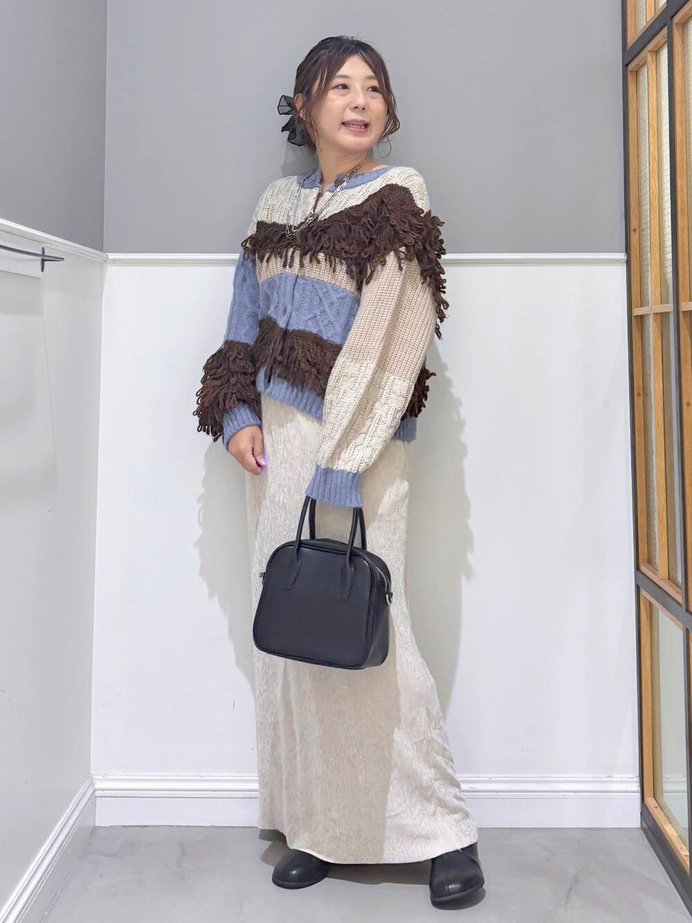 ブラック系のボストンバッグ、ブルー系のカーディガン/ボレロ、ブラック系のブーツを着用したレディースの秋コーディネートの2枚目の写真