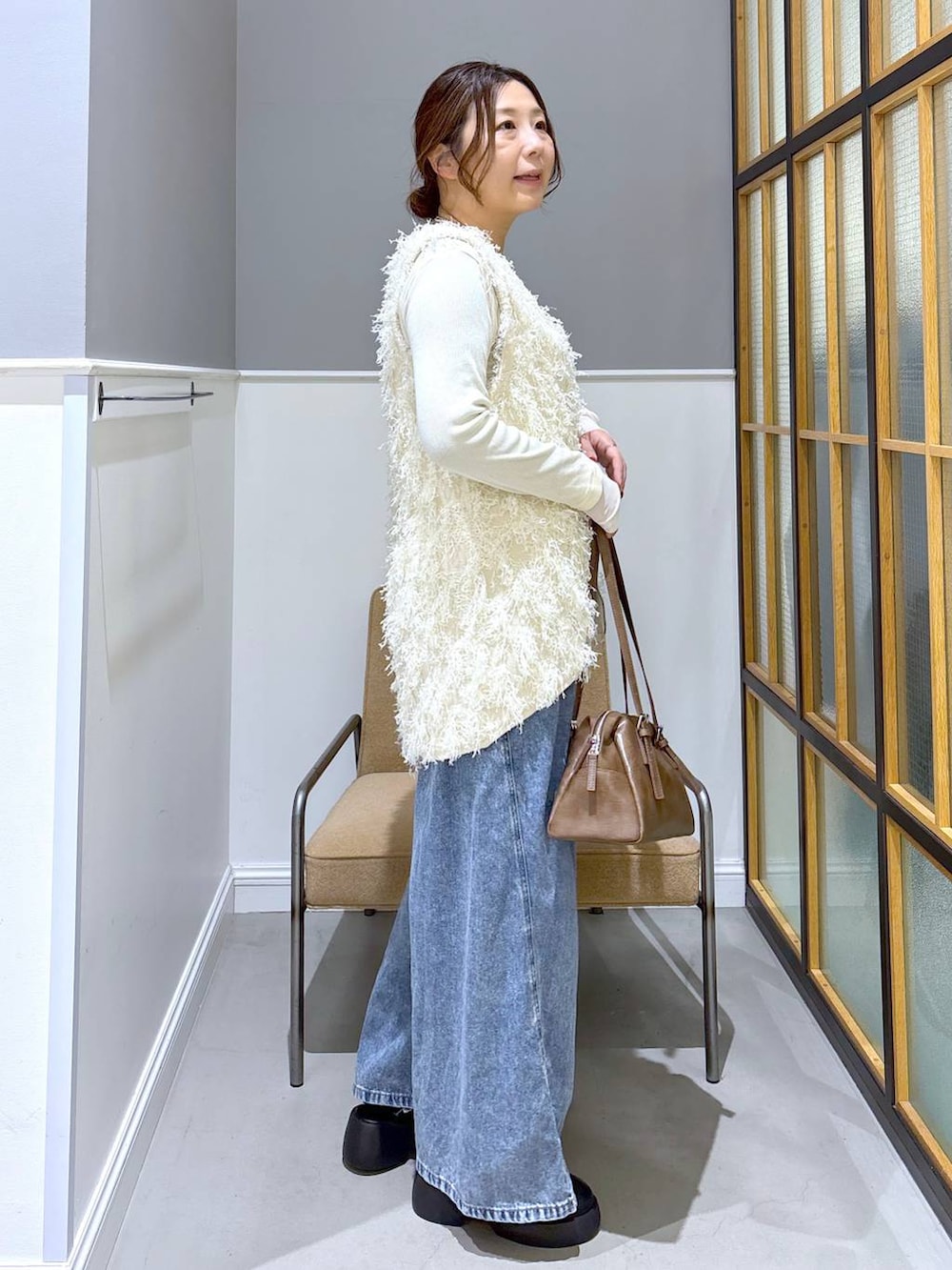 ブラック系のサンダル、ブラウン系のボストンバッグ、ホワイト系のTシャツ/カットソーを着用したレディースの冬コーディネートの4枚目の写真