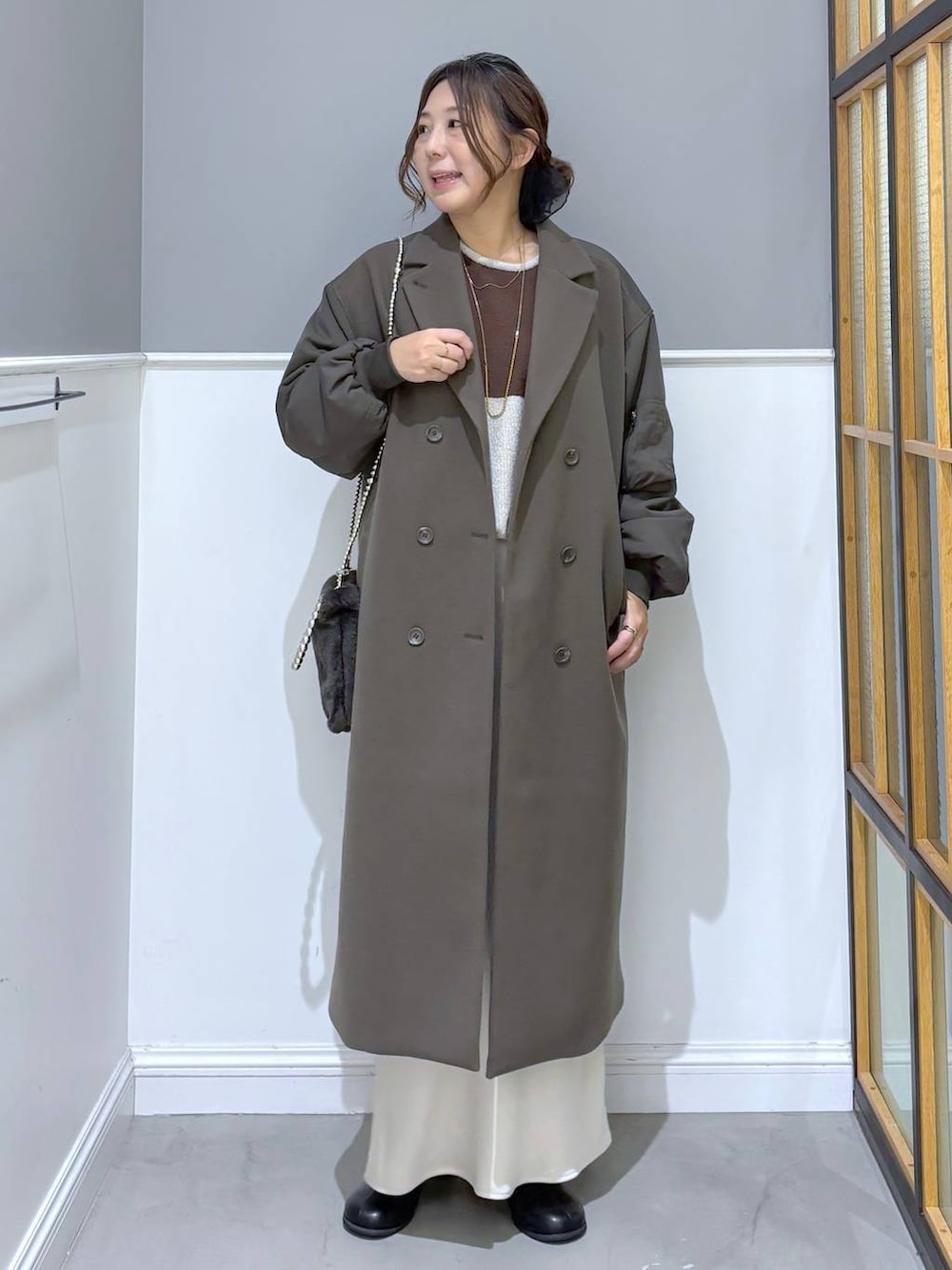 ホワイト系のスカート、ブラック系のブーツ、グレー系のショルダーバッグを着用したレディースの秋コーディネートの2枚目の写真