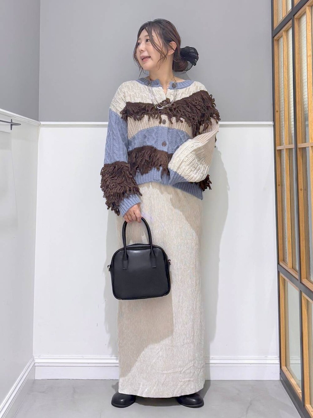 ブラック系のボストンバッグ、ブルー系のカーディガン/ボレロ、ブラック系のブーツを着用したレディースの秋コーディネートの6枚目の写真