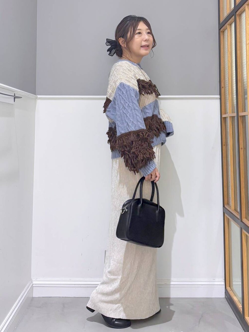 ブラック系のボストンバッグ、ブルー系のカーディガン/ボレロ、ブラック系のブーツを着用したレディースの秋コーディネートの5枚目の写真