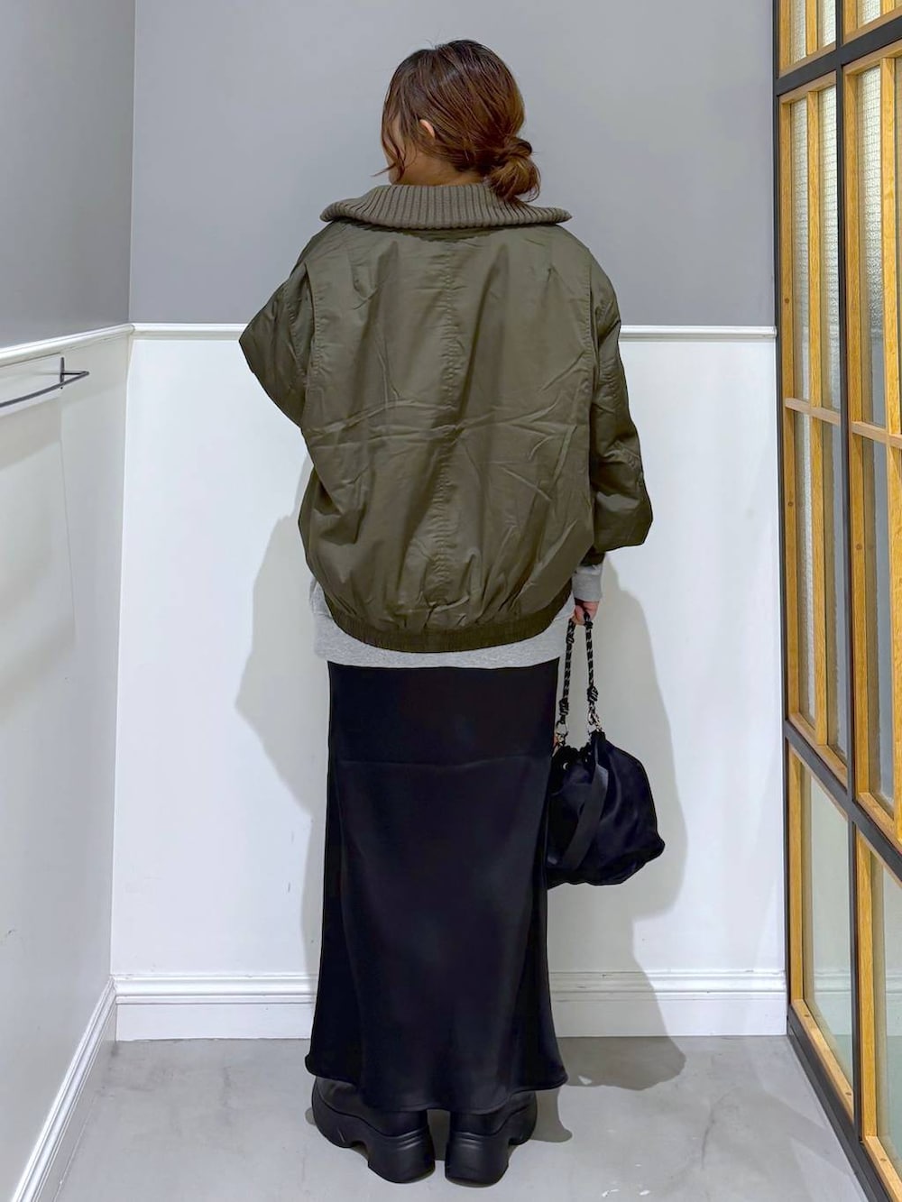 ブラック系のショルダーバッグ、ブラック系のスカート、ブラック系のブーツを着用したレディースの秋コーディネートの4枚目の写真