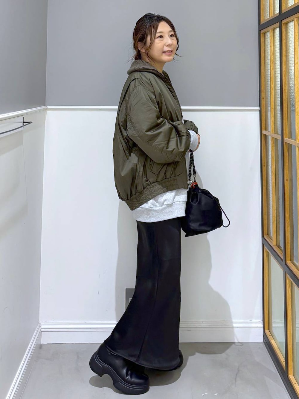 ブラック系のショルダーバッグ、ブラック系のスカート、ブラック系のブーツを着用したレディースの秋コーディネートの5枚目の写真