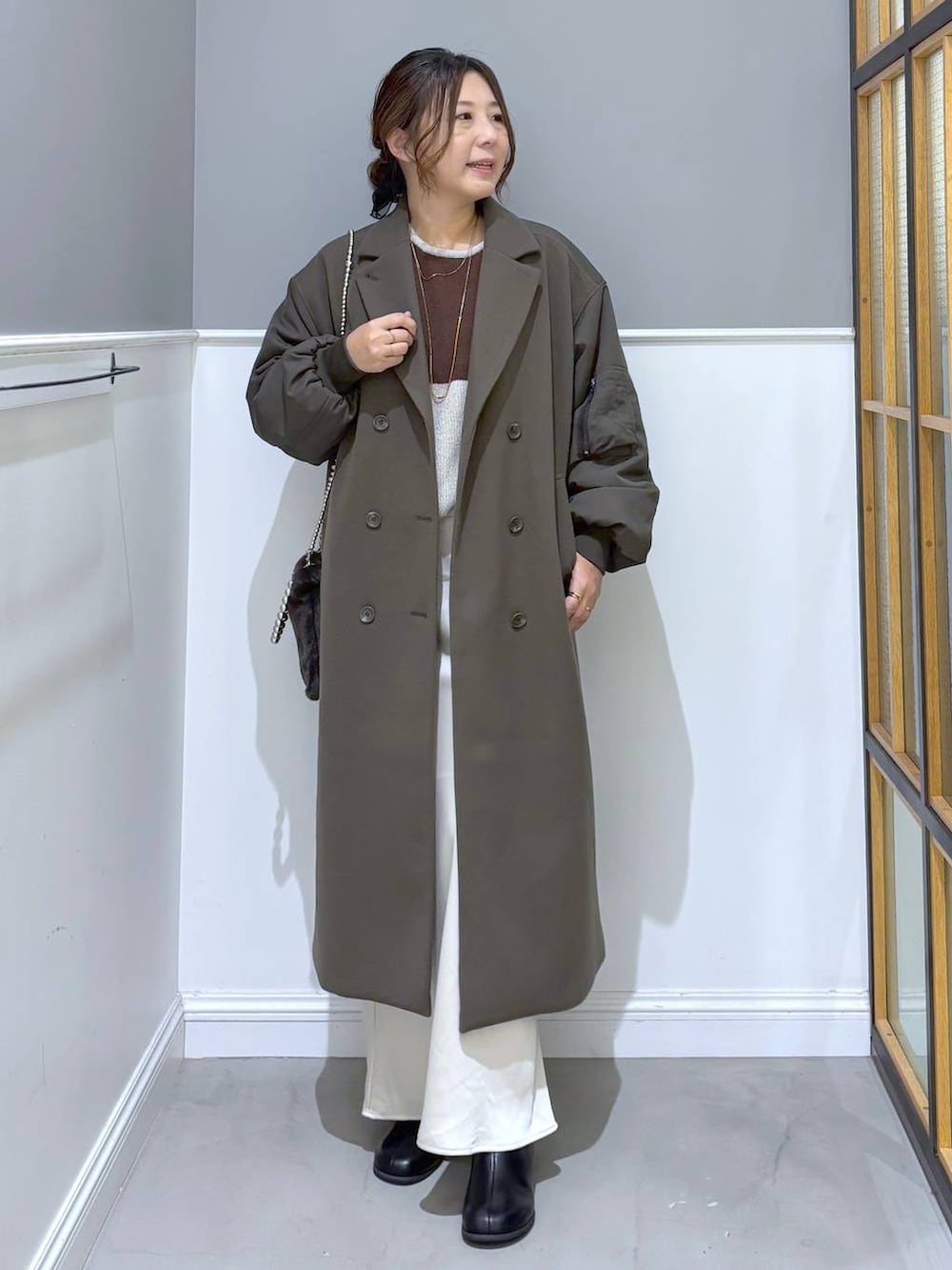 ホワイト系のスカート、ブラック系のブーツ、グレー系のショルダーバッグを着用したレディースの秋コーディネートの6枚目の写真