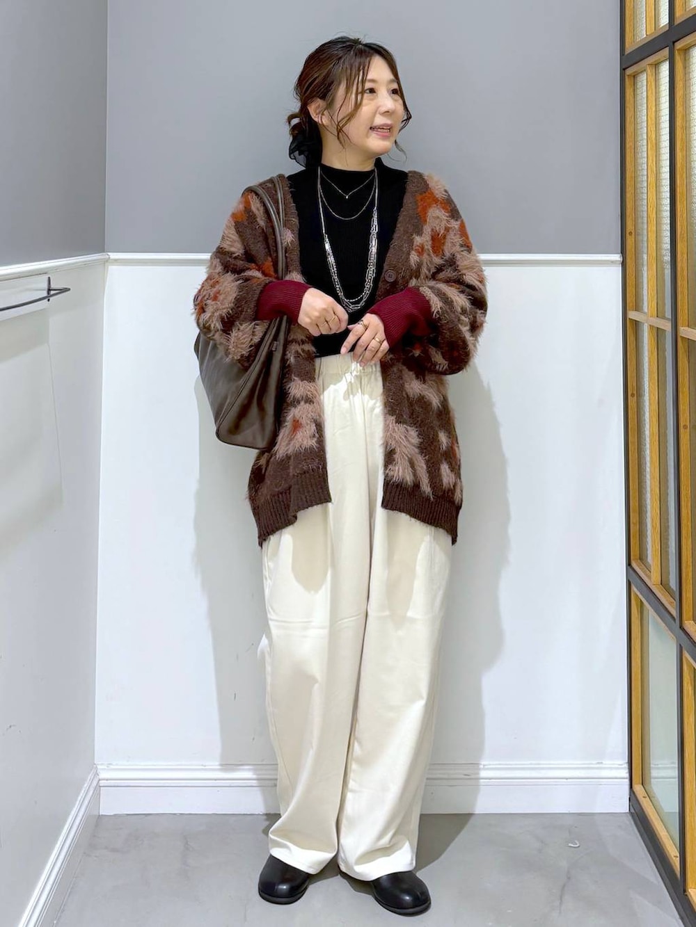 ブラック系のニット/セーター、ホワイト系のその他パンツ、ブラウン系のトートバッグを着用したレディースの秋コーディネートの5枚目の写真