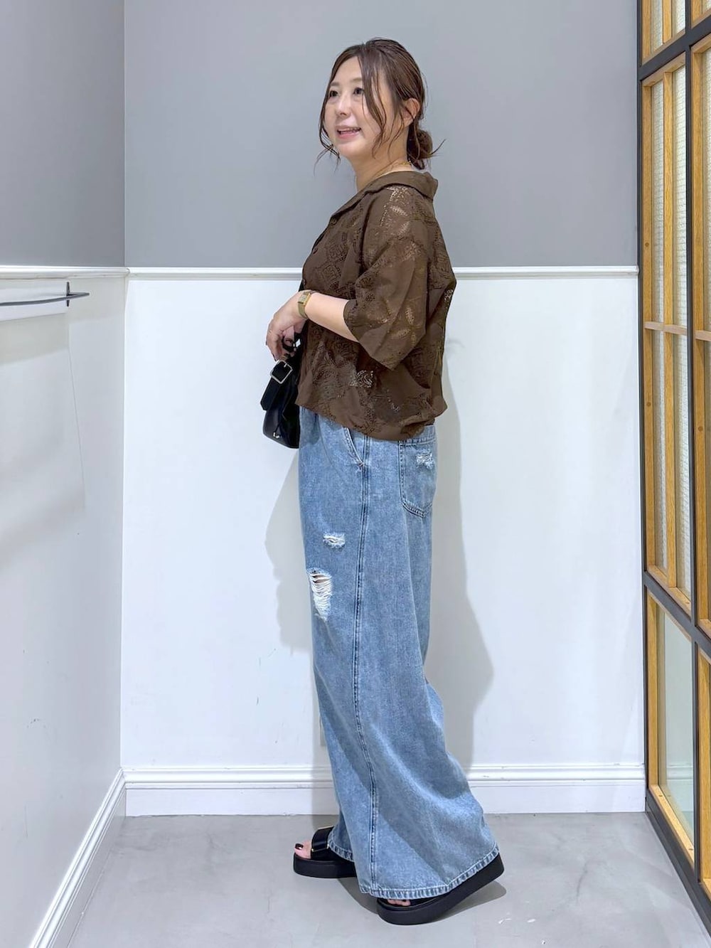 ブラウン系のシャツ/ブラウス、ブルー系のデニムパンツ、ブラック系のショルダーバッグを着用したレディースの夏コーディネートの2枚目の写真