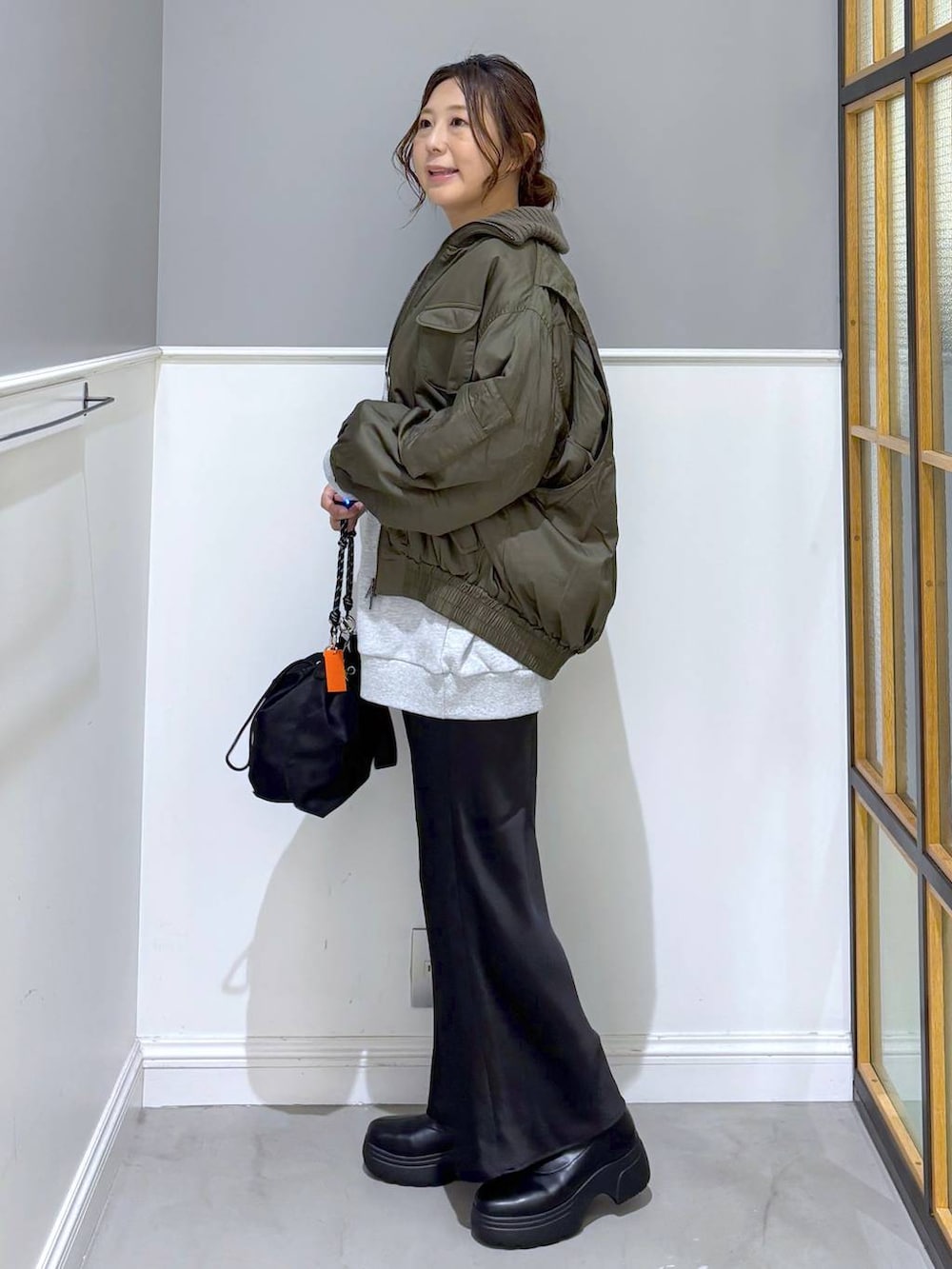 ブラック系のショルダーバッグ、ブラック系のスカート、ブラック系のブーツを着用したレディースの秋コーディネートの3枚目の写真