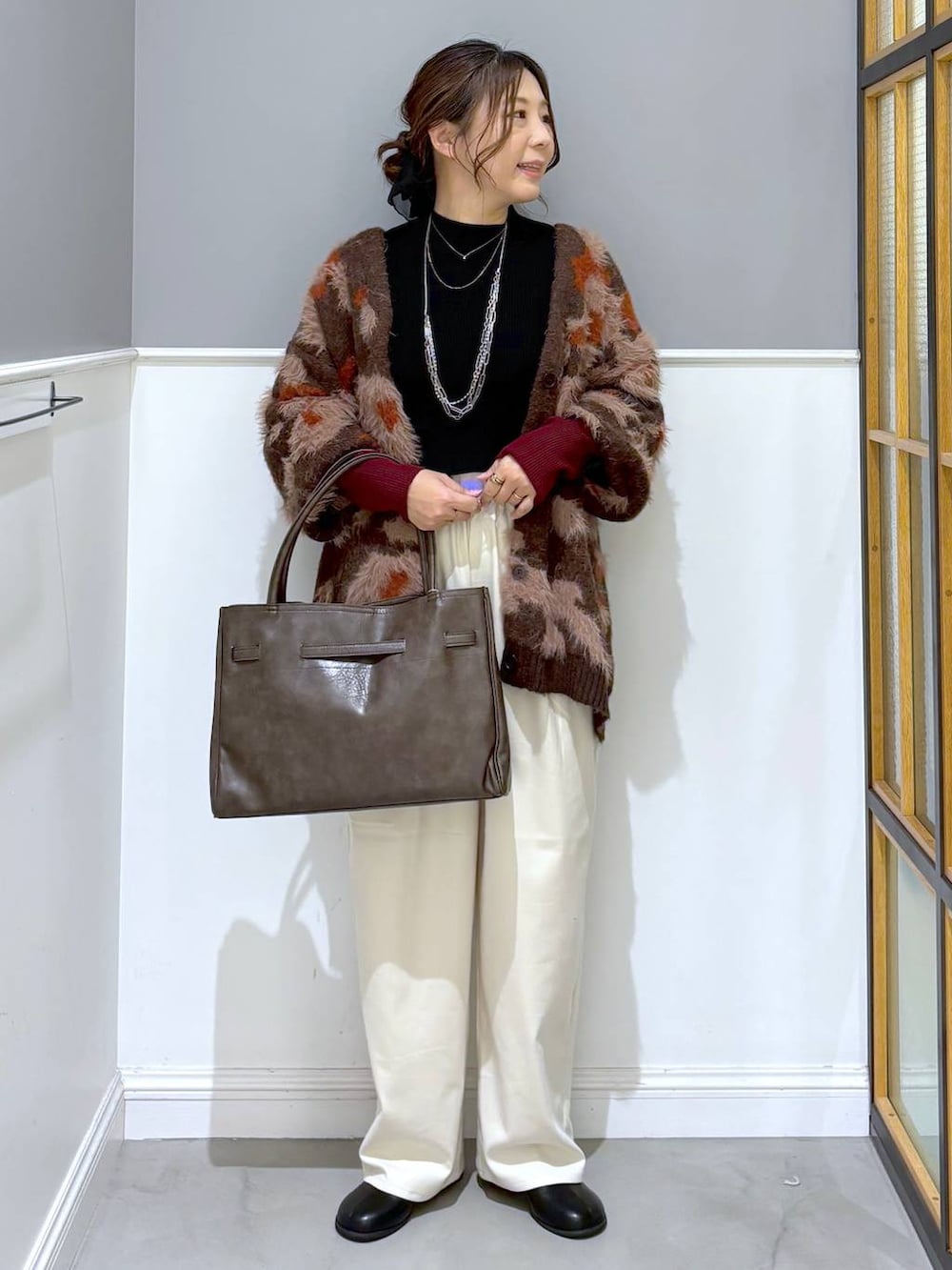 ブラック系のニット/セーター、ホワイト系のその他パンツ、ブラウン系のトートバッグを着用したレディースの秋コーディネートの2枚目の写真
