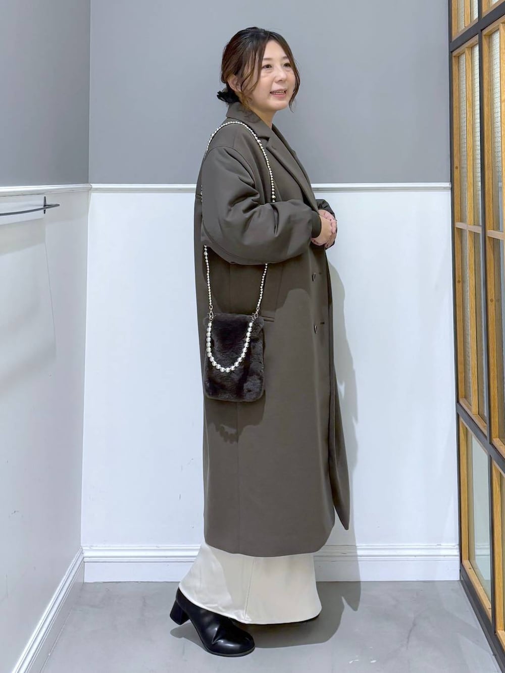 ホワイト系のスカート、ブラック系のブーツ、グレー系のショルダーバッグを着用したレディースの秋コーディネートの5枚目の写真