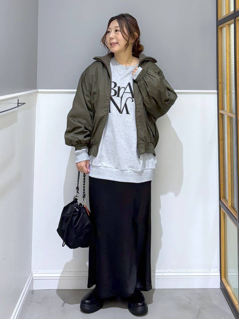 ブラック系のショルダーバッグ、ブラック系のスカート、ブラック系のブーツを着用したレディースの秋コーディネートの2枚目の写真