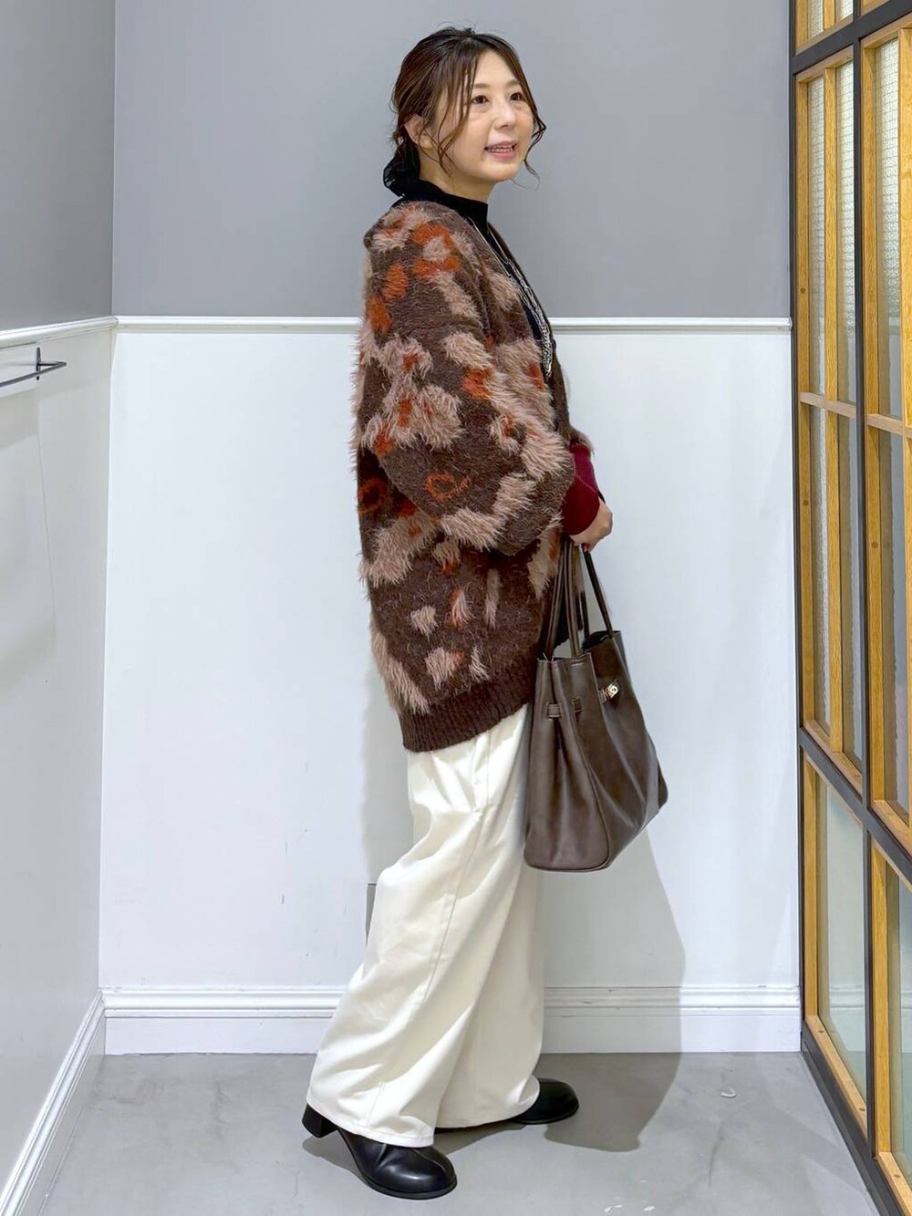 ブラック系のニット/セーター、ホワイト系のその他パンツ、ブラウン系のトートバッグを着用したレディースの秋コーディネートの4枚目の写真