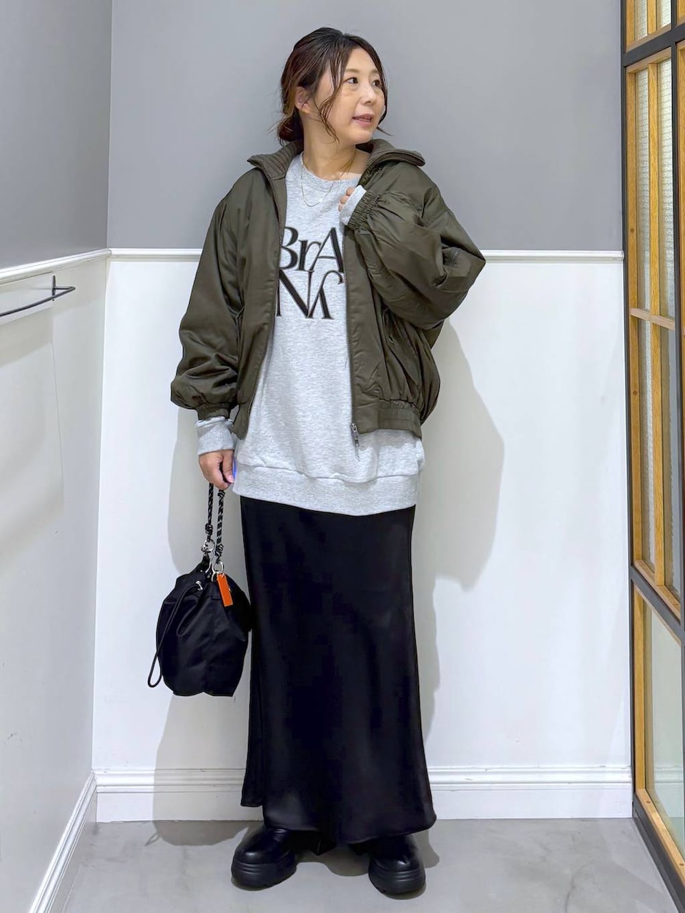 ブラック系のショルダーバッグ、ブラック系のスカート、ブラック系のブーツを着用したレディースの秋コーディネートの6枚目の写真