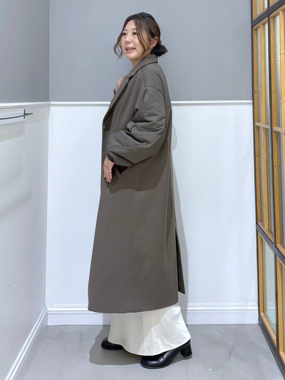 ホワイト系のスカート、ブラック系のブーツ、グレー系のショルダーバッグを着用したレディースの秋コーディネートの3枚目の写真