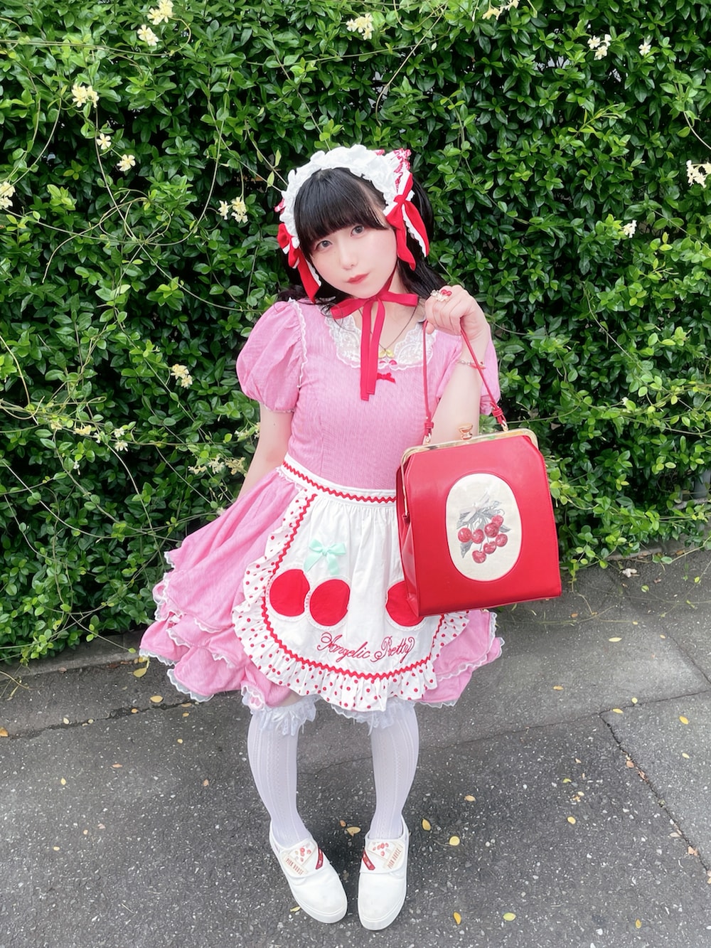 レッド系のハンドバッグ、レッド系のワンピース、ホワイト系のスニーカーを着用したレディースの夏コーディネートの2枚目の写真