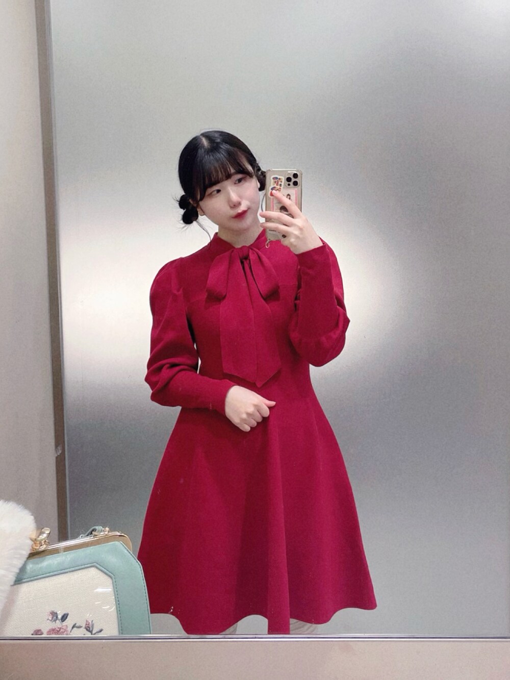 レッド系のワンピース、ホワイト系のノーカラージャケット、グリーン系のハンドバッグを着用したレディースの冬コーディネートの2枚目の写真