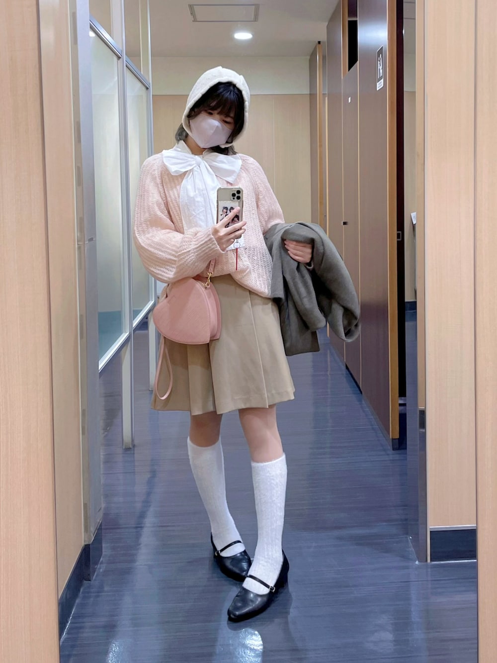 ピンク系のニット/セーター、ピンク系のハンドバッグ、ホワイト系のシャツ/ブラウスを着用したレディースの冬コーディネートの2枚目の写真