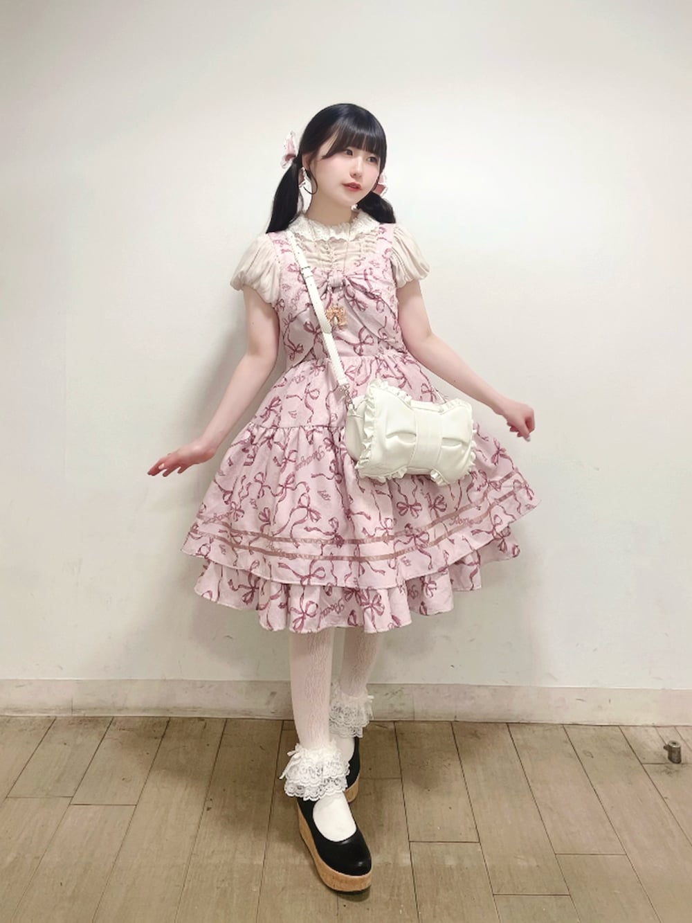 ピンク系のジャンパースカート、ホワイト系のショルダーバッグ、ブラック系のパンプスを着用したレディースの春コーディネートの2枚目の写真