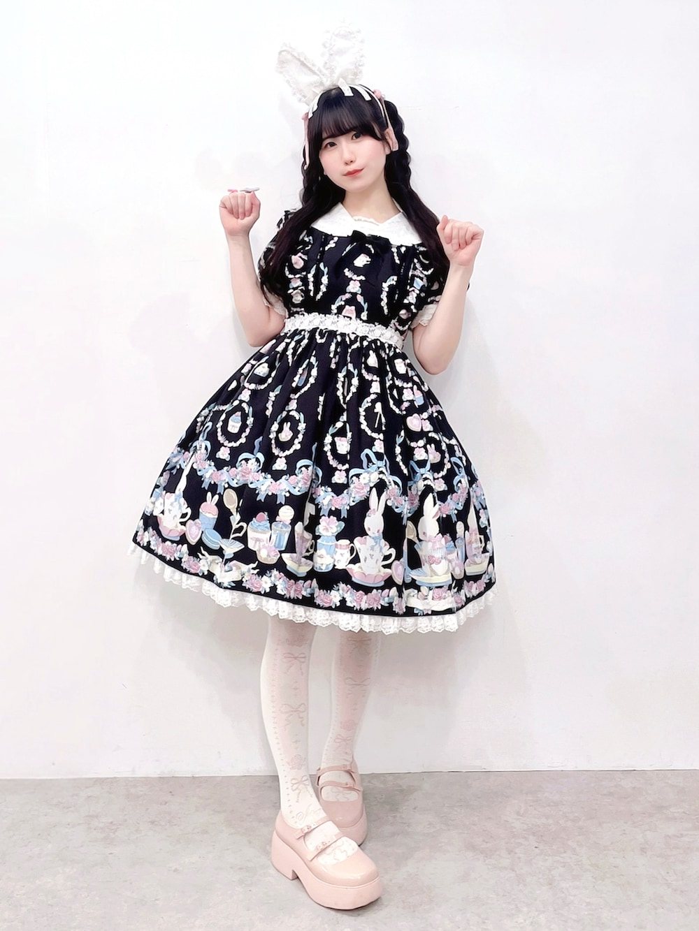 ブラック系のワンピース/ドレス、ピンク系のカーディガン/ボレロ、ピンク系のパンプスを着用したレディースの春コーディネートの2枚目の写真