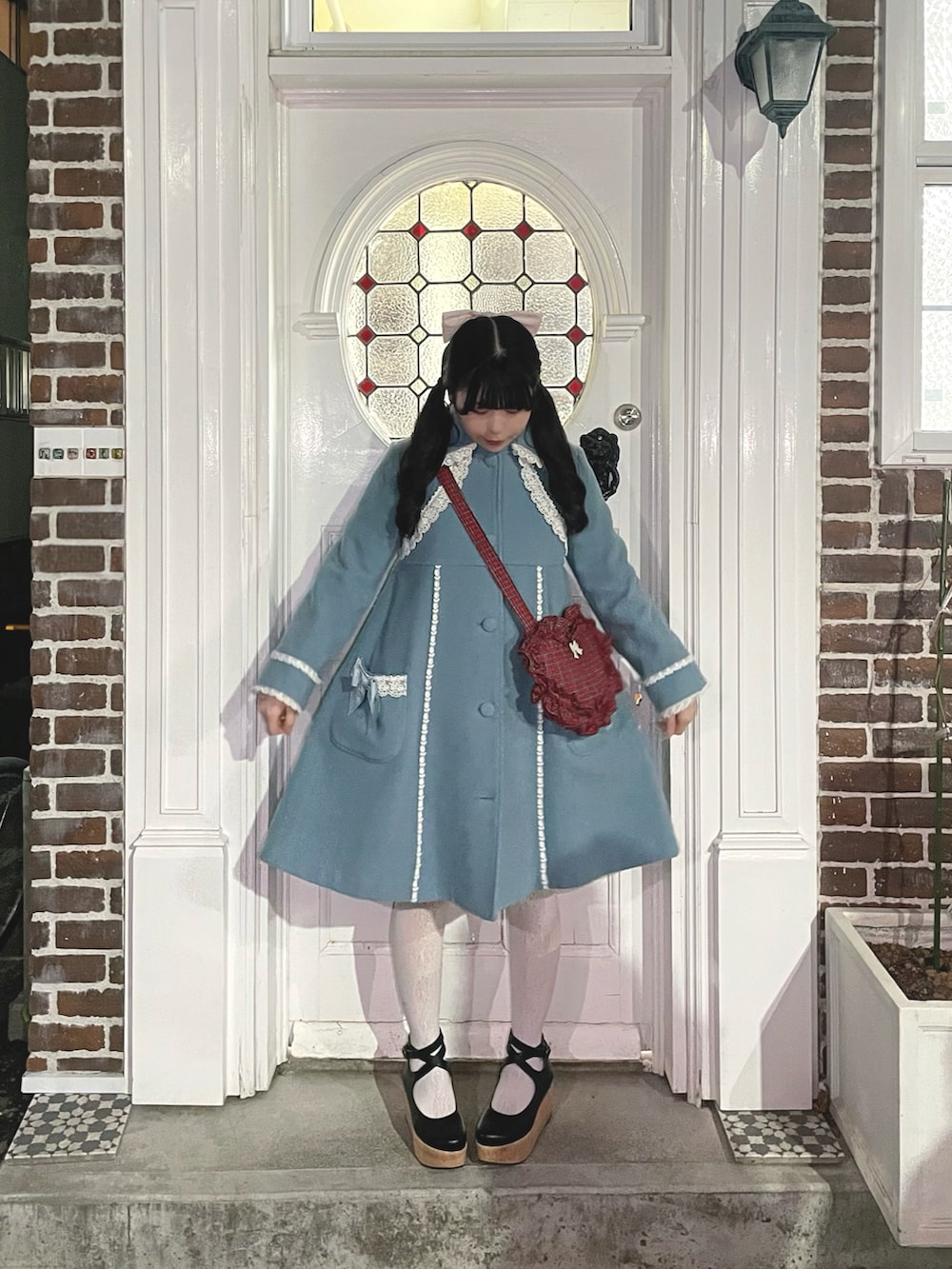 ピンク系のワンピース、グリーン系のハンドバッグ、ブラック系のパンプスを着用したレディースの冬コーディネートの3枚目の写真