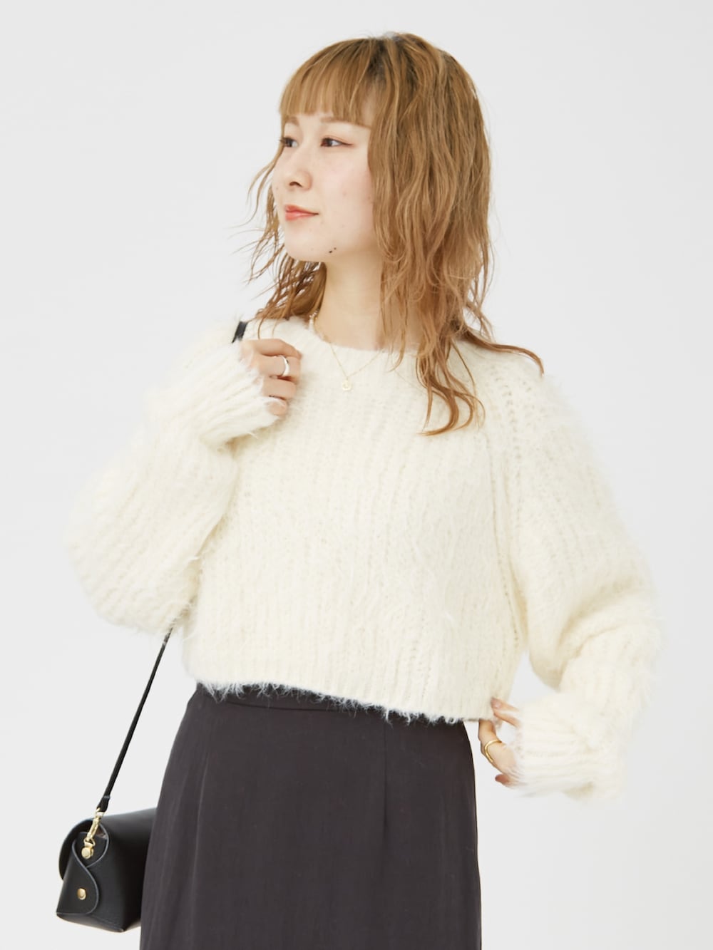 ホワイト系のニット/セーター、ブラック系のパンプス、ブラック系のショルダーバッグを着用したレディースの冬コーディネートの5枚目の写真