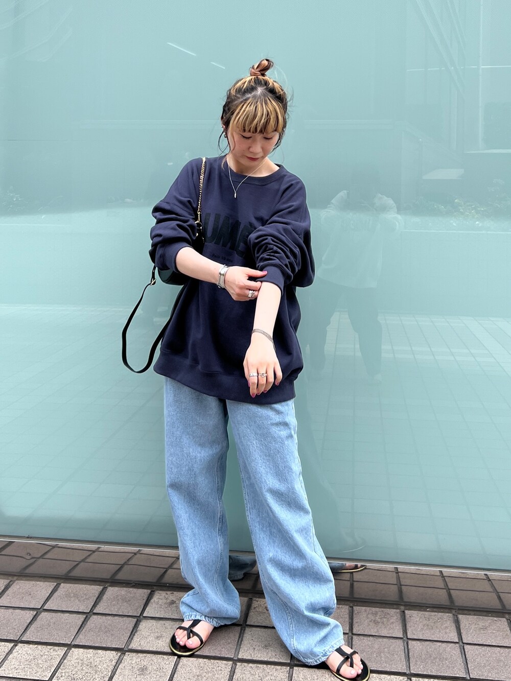 ブルー系のスウェット、ブルー系のデニムパンツ、ブラック系のサンダルを着用したレディースの秋コーディネートの3枚目の写真