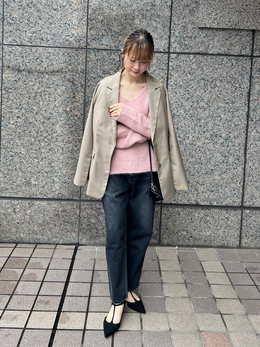 ピンク系のニット/セーター、ベージュ系のセットアップ、ブラック系のショルダーバッグを着用したレディースの秋コーディネートの2枚目の写真