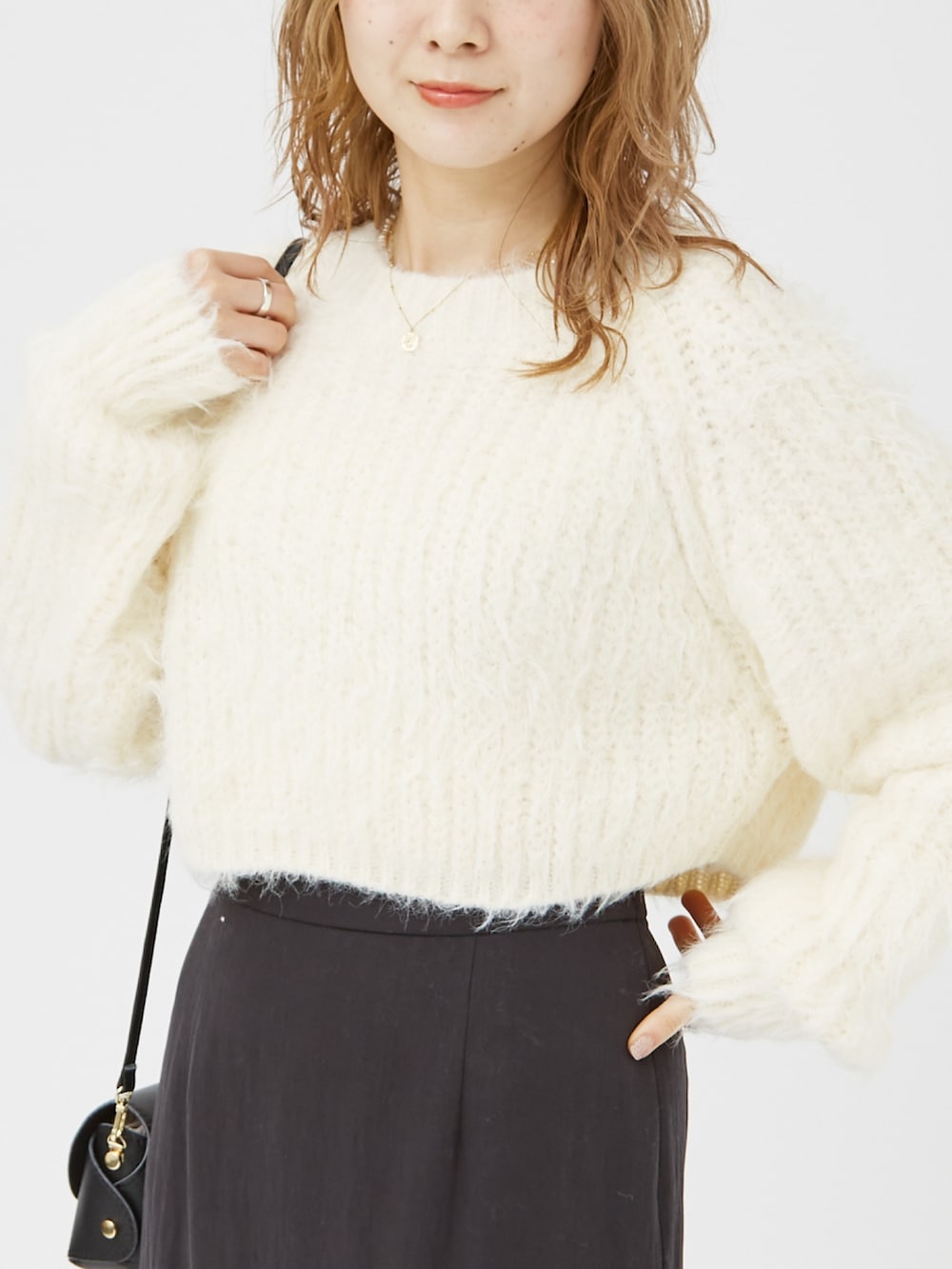 ホワイト系のニット/セーター、ブラック系のパンプス、ブラック系のショルダーバッグを着用したレディースの冬コーディネートの4枚目の写真