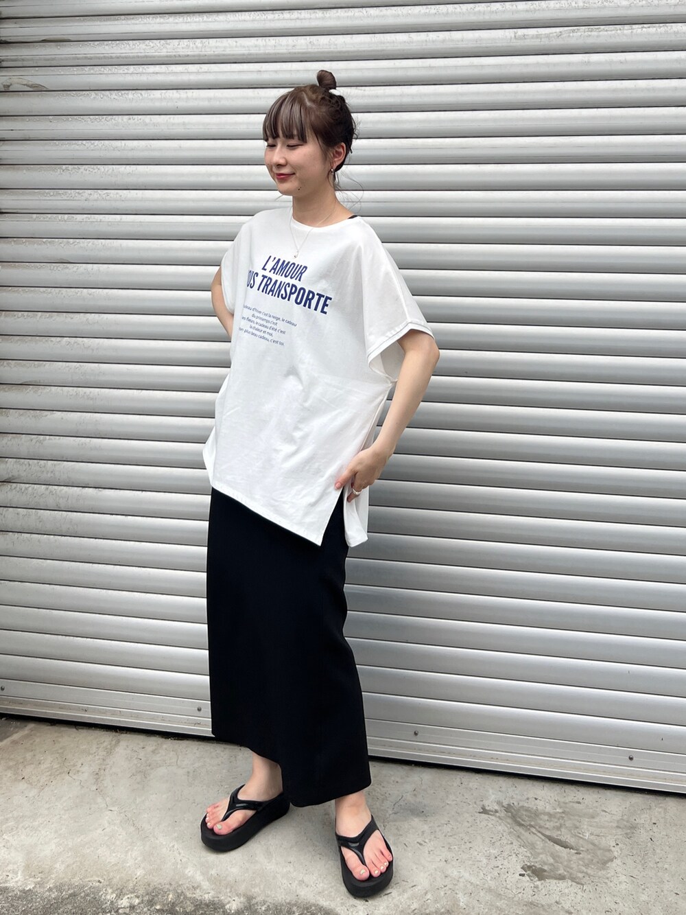 ブルー系のTシャツ/カットソー、ブラック系のスカート、ブラック系のサンダルを着用したレディースの夏コーディネートの2枚目の写真