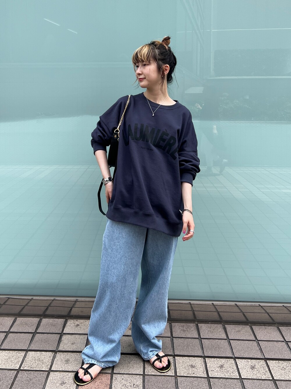 ブルー系のスウェット、ブルー系のデニムパンツ、ブラック系のサンダルを着用したレディースの秋コーディネートの2枚目の写真