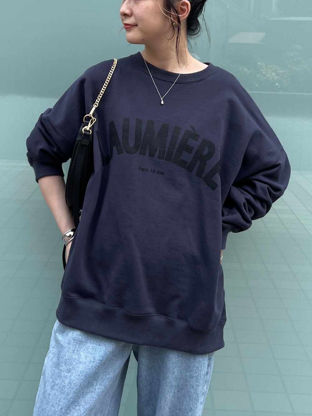 ブルー系のスウェット、ブルー系のデニムパンツ、ブラック系のサンダルを着用したレディースの秋コーディネートの6枚目の写真