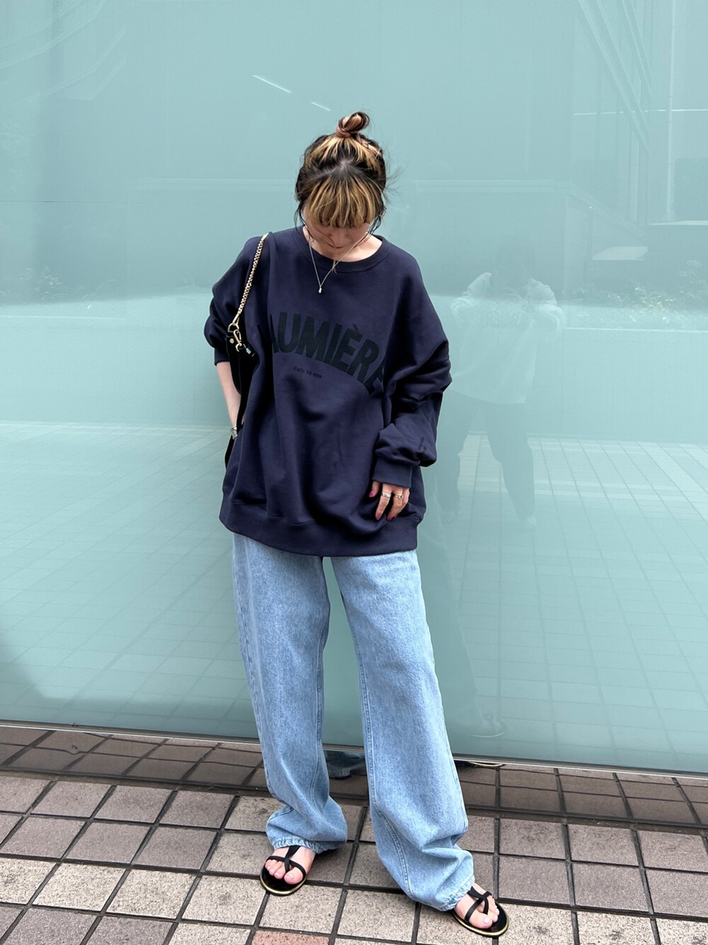 ブルー系のスウェット、ブルー系のデニムパンツ、ブラック系のサンダルを着用したレディースの秋コーディネートの4枚目の写真