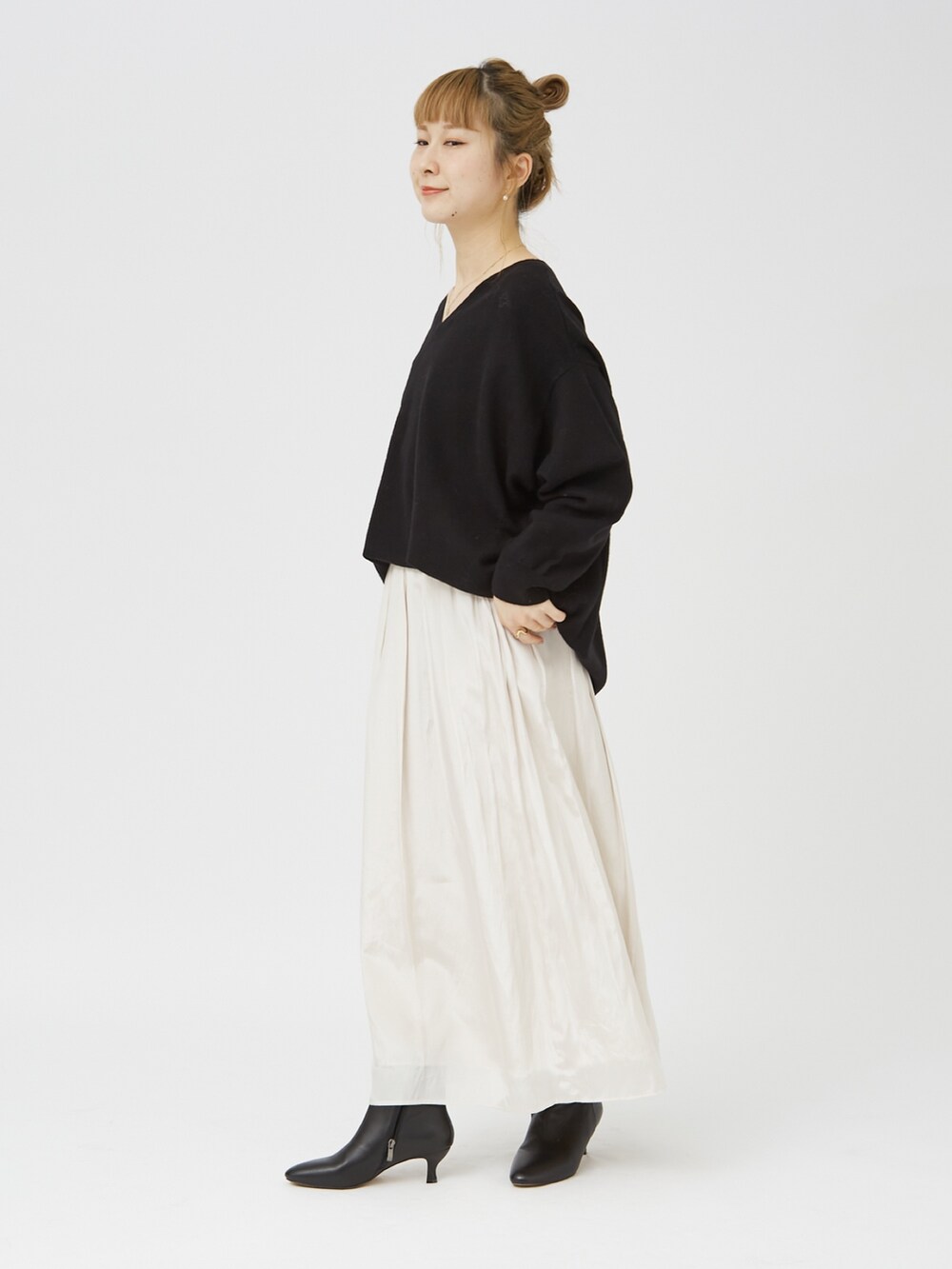 ブラック系のニット/セーター、ホワイト系のスカート、ブラック系のブーツを着用したレディースの冬コーディネートの2枚目の写真