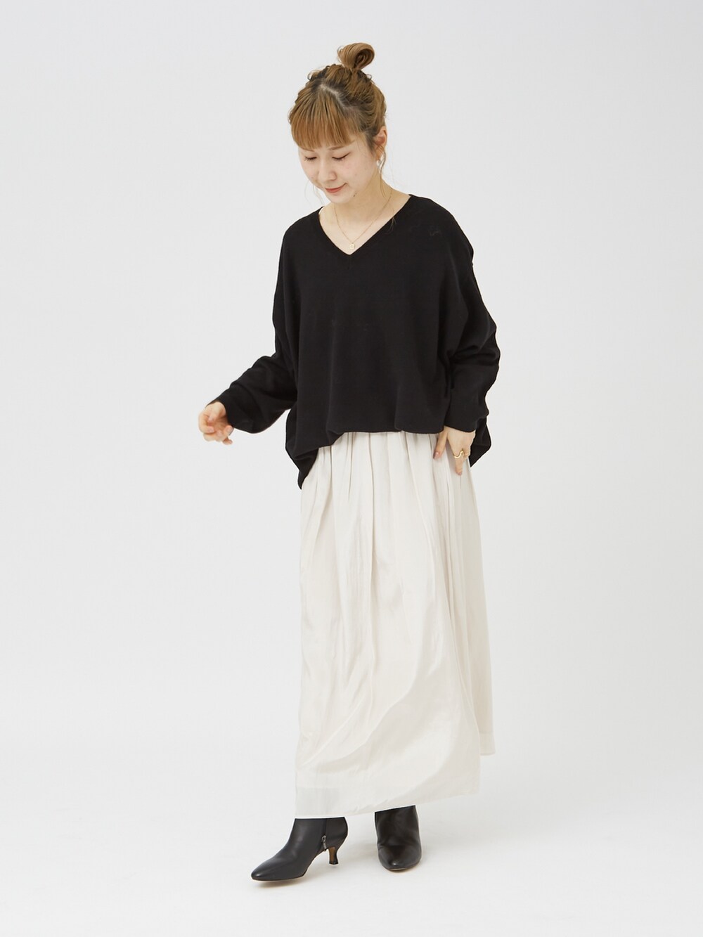 ブラック系のニット/セーター、ホワイト系のスカート、ブラック系のブーツを着用したレディースの冬コーディネートの3枚目の写真