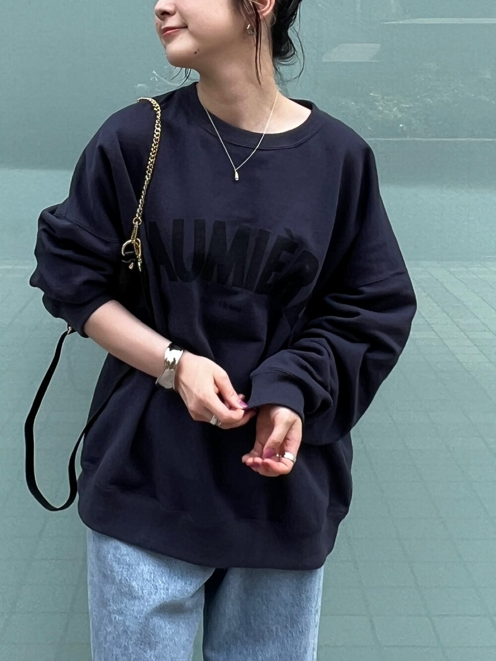 ブルー系のスウェット、ブルー系のデニムパンツ、ブラック系のサンダルを着用したレディースの秋コーディネートの5枚目の写真