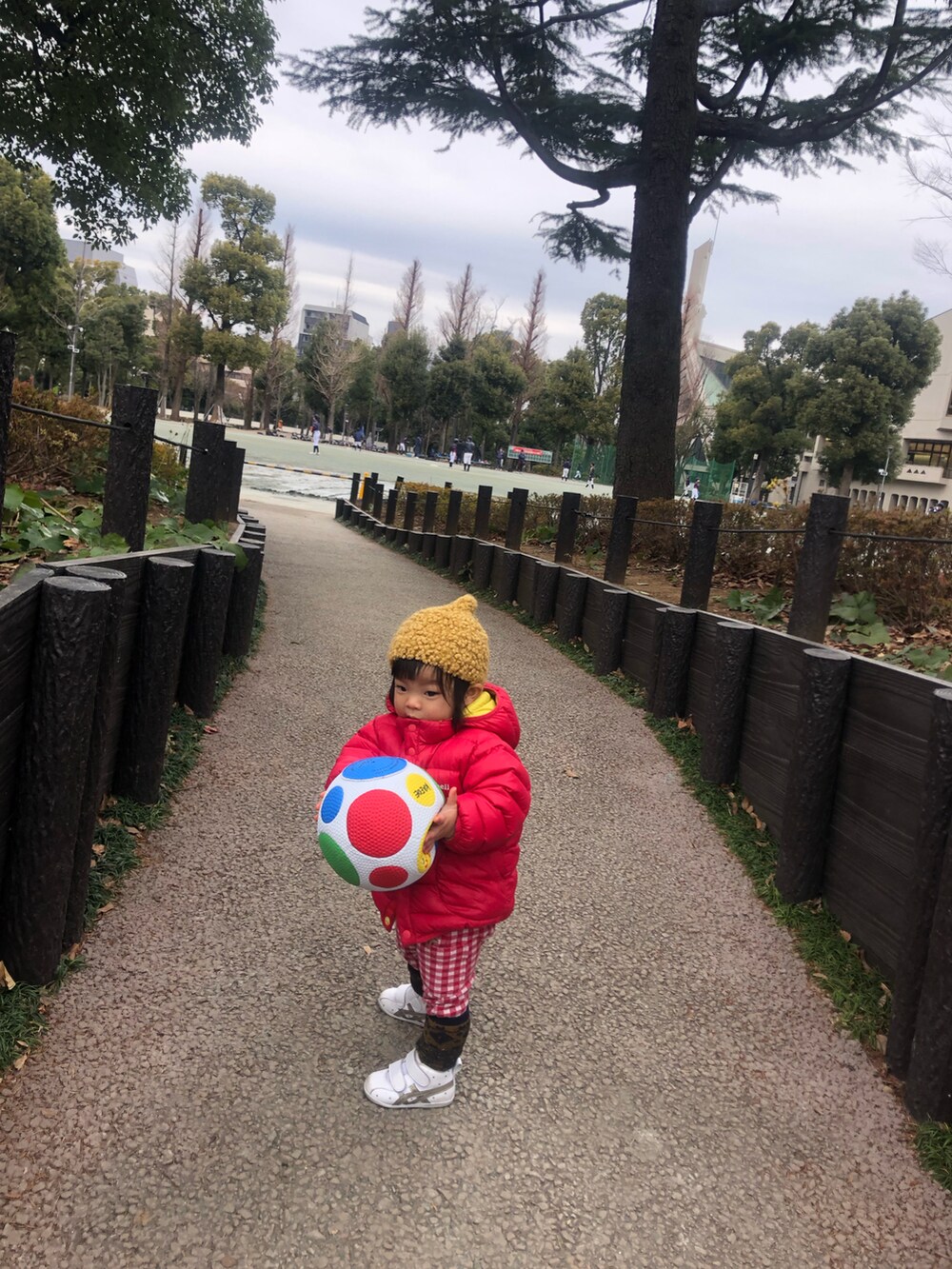 レッド系のダウンジャケット/コート、レッド系のパンツ、ホワイト系のスニーカーを着用したレディースの冬コーディネートの5枚目の写真