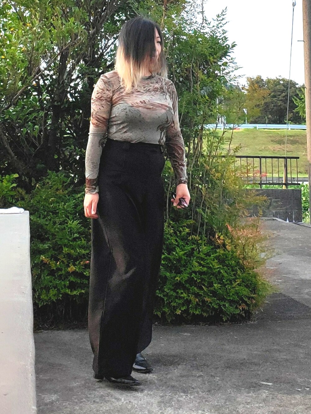 ブラック系のスラックス、グリーン系のTシャツ/カットソー、ブラック系のパンプスを着用したレディースの秋コーディネートの4枚目の写真