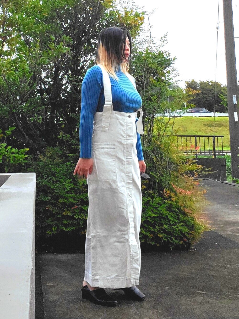 ブラック系のパンプス、ホワイト系のジャンパースカート、ブルー系のニット/セーターを着用したレディースの秋コーディネートの3枚目の写真