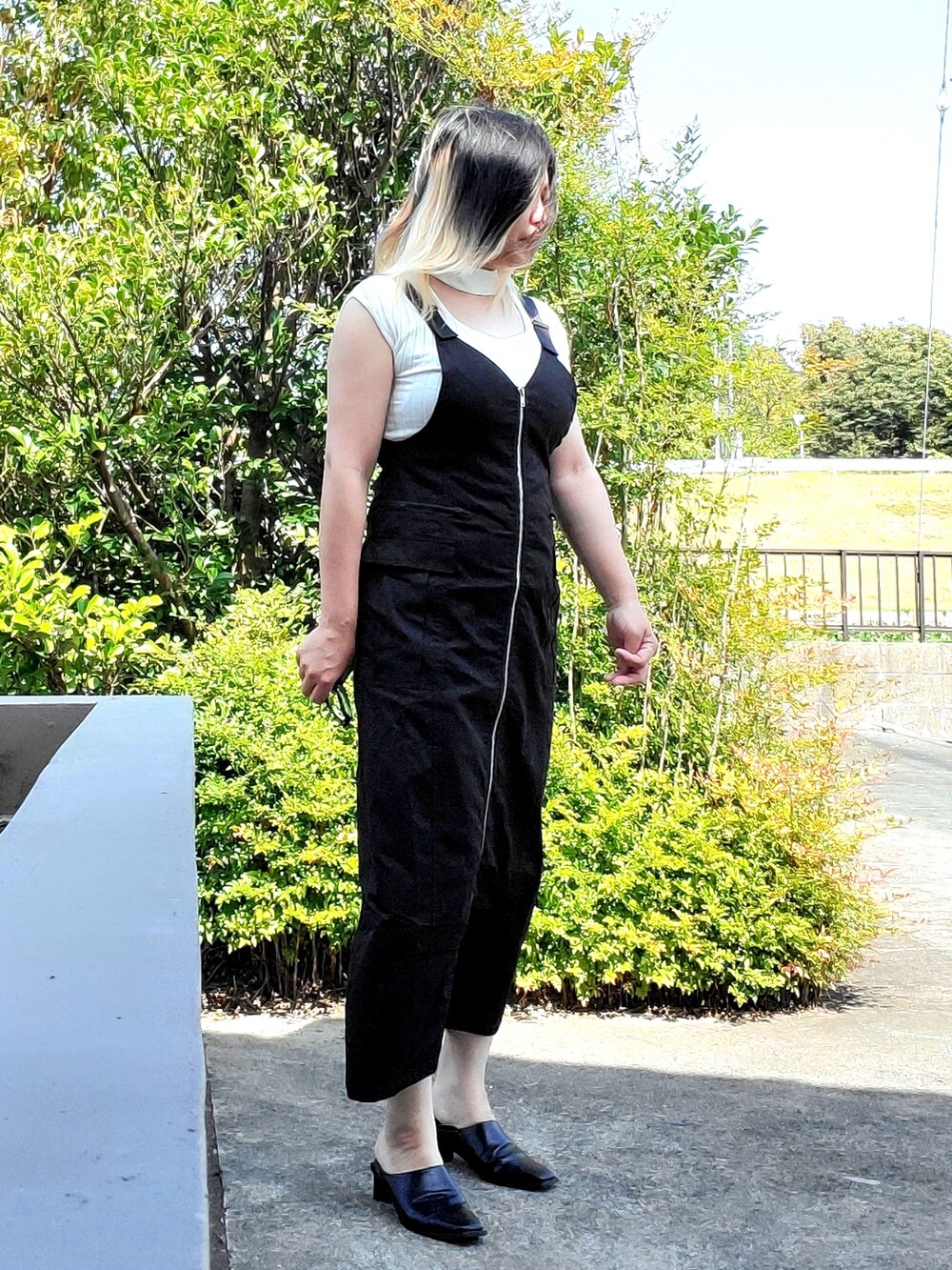 ブラック系のジャンパースカート、ホワイト系のニット/セーター、ブラック系のパンプスを着用したレディースの秋コーディネートの4枚目の写真