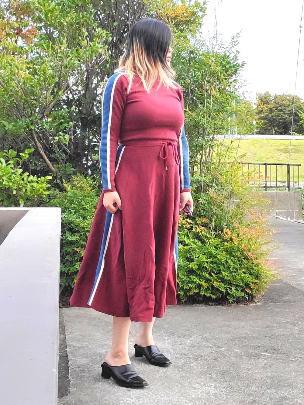 レッド系のワンピース、ブラック系のパンプスを着用したレディースの秋コーディネートの2枚目の写真