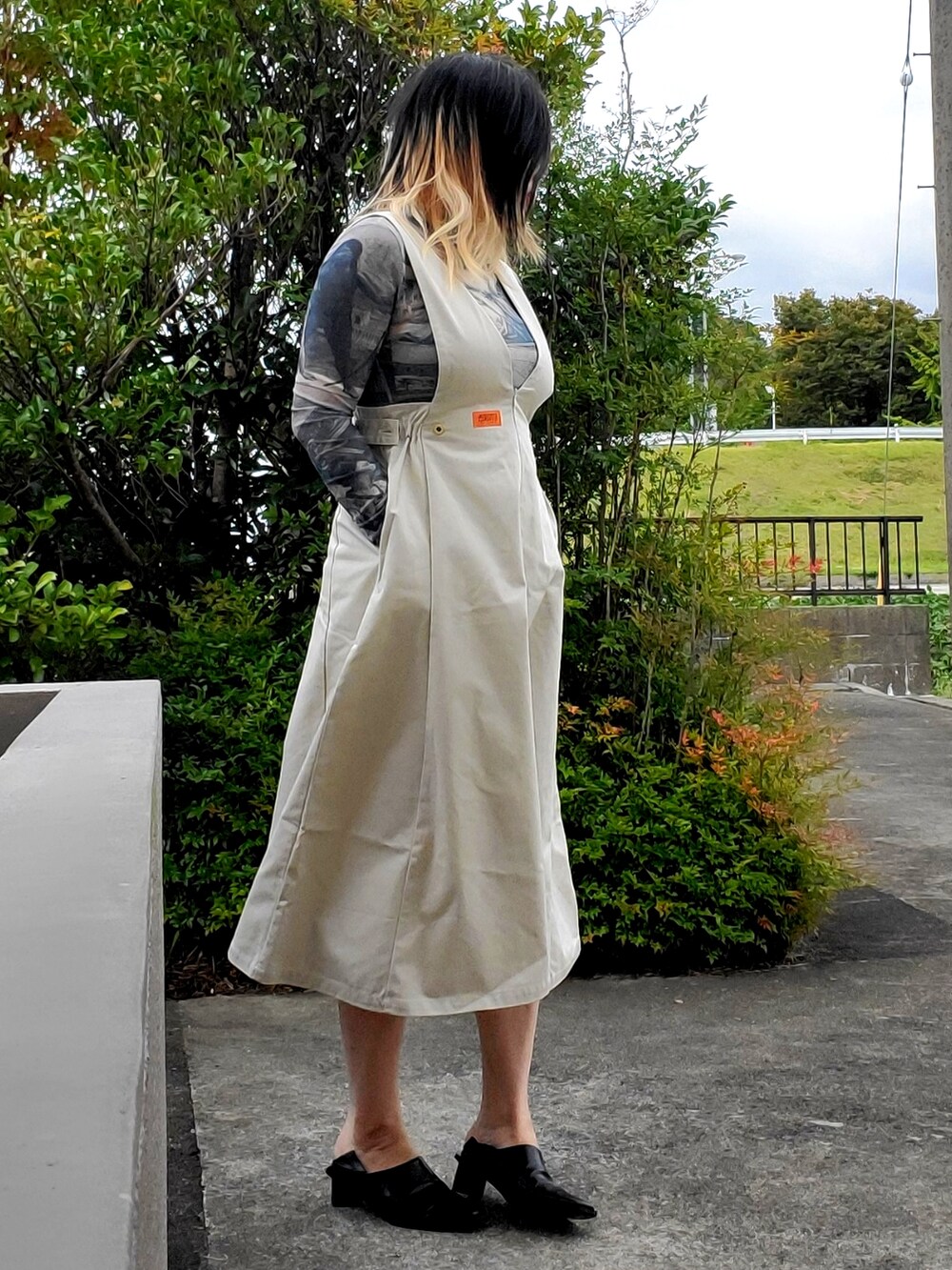 ホワイト系のジャンパースカート、ブラック系のパンプス、ブルー系のTシャツ/カットソーを着用したレディースの秋コーディネートの2枚目の写真