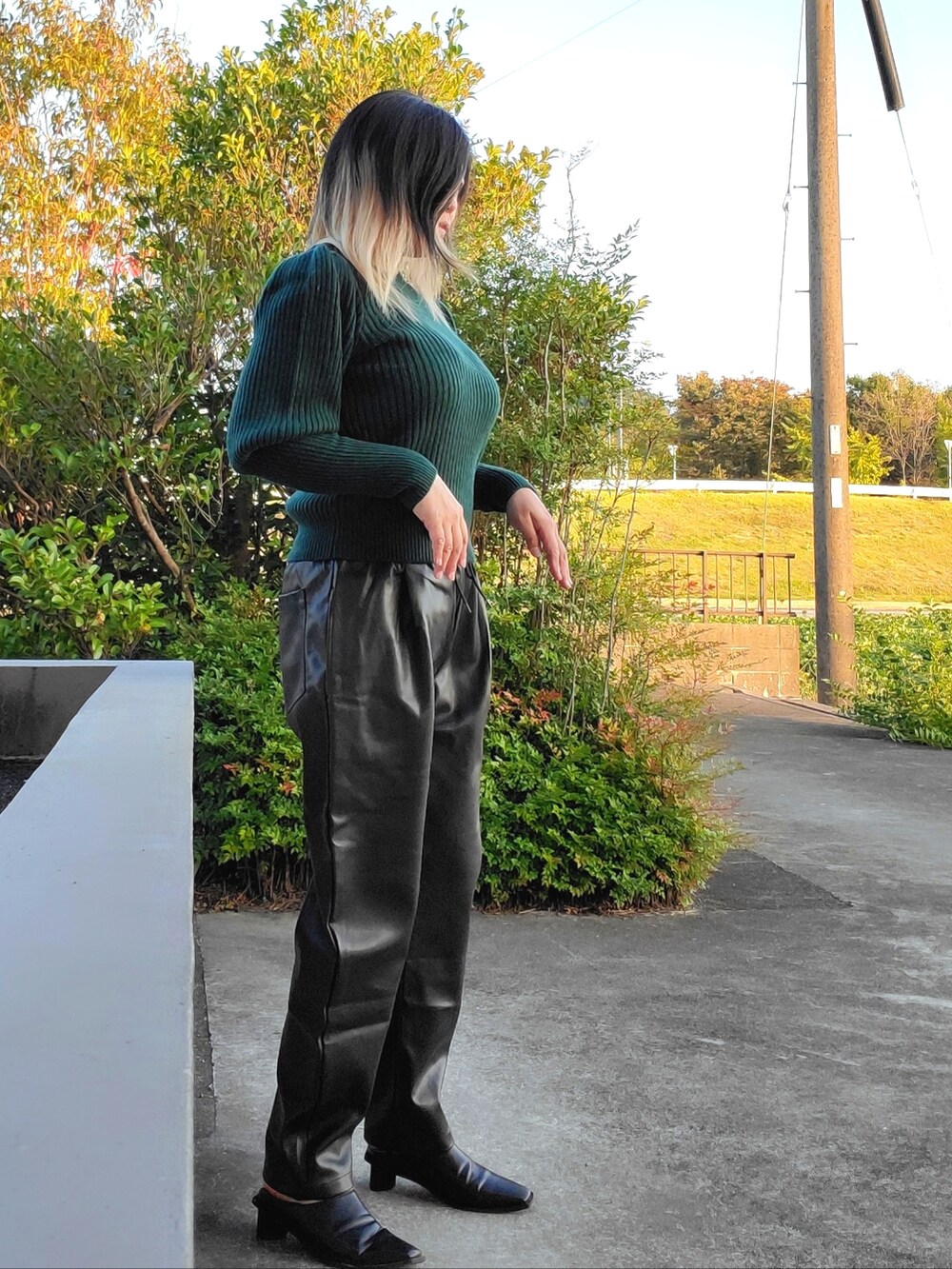 グレー系のその他パンツ、ブラック系のパンプス、グリーン系のニット/セーターを着用したレディースの秋コーディネートの2枚目の写真