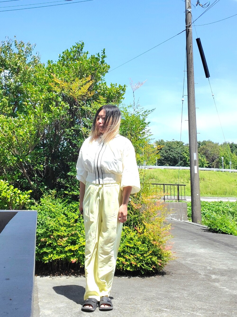 イエロー系のその他パンツ、ホワイト系のブルゾンを着用したレディースの夏コーディネートの2枚目の写真