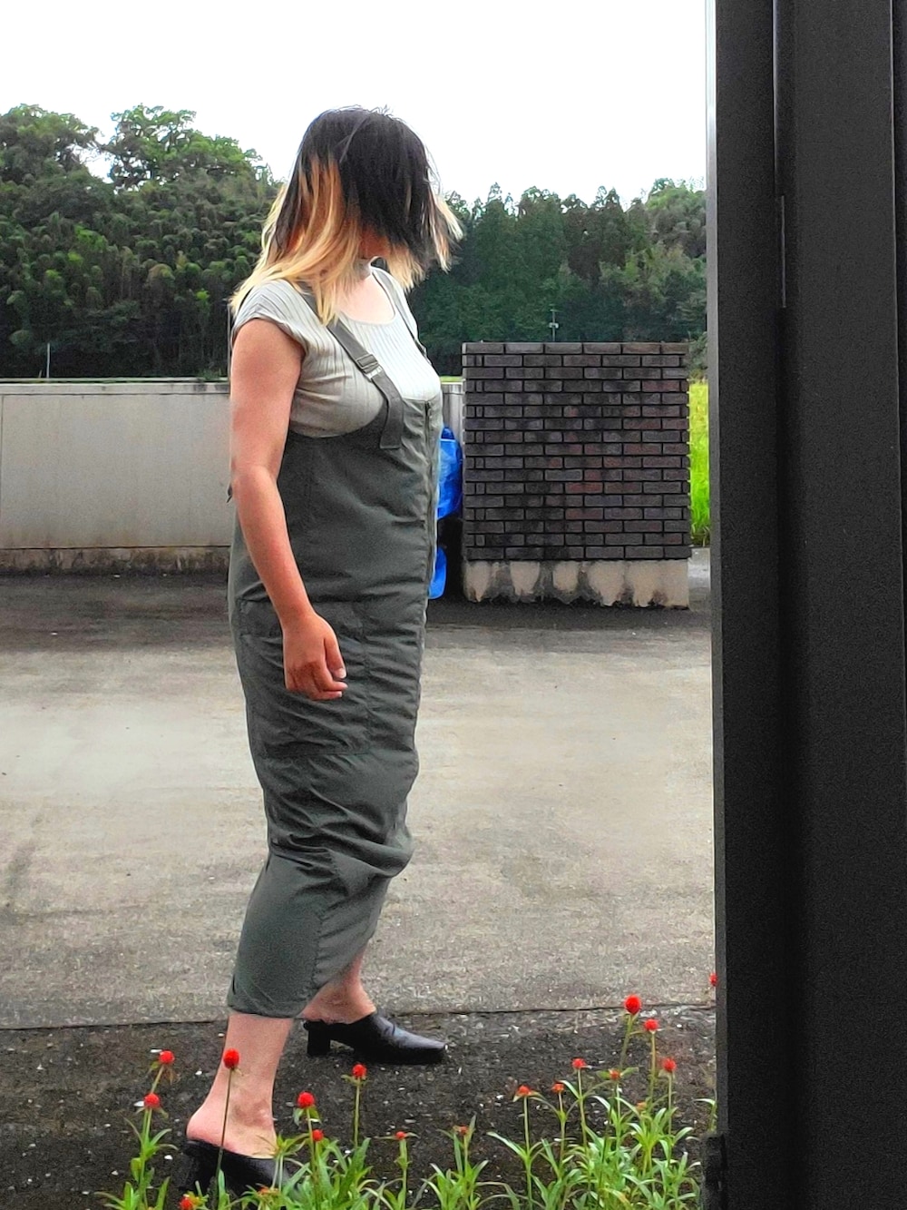 グリーン系のジャンパースカート、ベージュ系のニット/セーター、ブラック系のパンプスを着用したレディースの秋コーディネートの3枚目の写真